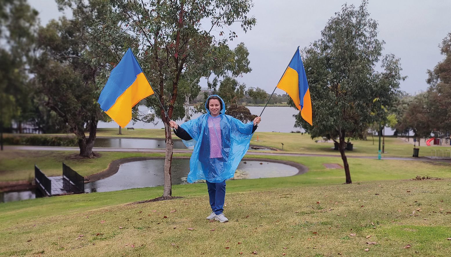 holding two Ukraine flags in rain